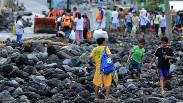 Residents cross a road covered in debris from a landslide triggered by Typhoon Nock-Ten in Tabaco, Albay province . At least six people are dead and 18 others missing after Typhoon Nock-Ten lashed the Philippines over the Christmas holidays, the government said. (Arlan B. Flores/AFP)