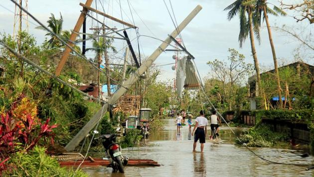 Residents walk past partially toppled electric posts after Typhoon Nock Ten hit Malinao, Albay in central Philippines. (Renellyn Loaquinario/REUTERS)