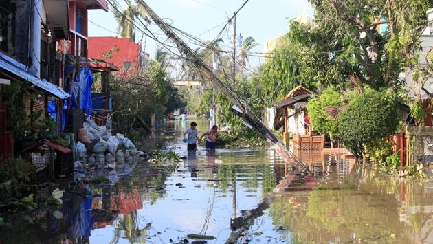Residents wade across a flooded street brought by heavy rains and strong winds of Typhoon Nock-ten. (Romeo Ranoco/REUTERS)