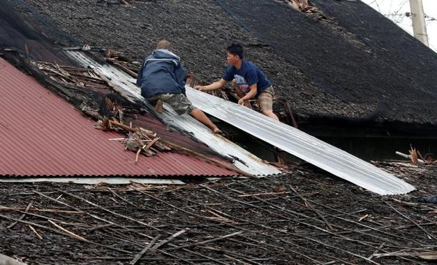 Residents fix their partially damaged roof after Typhoon Nock Ten hit Mabini, Batangas in the Philippines. (Erik De Castro/Reuters)