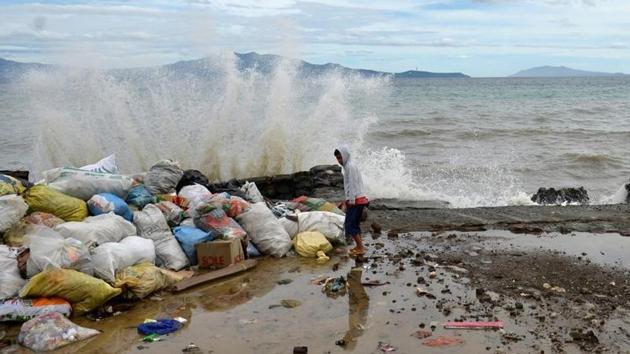 A boy stands at a partially damaged port, as strong waves hit the shore after Typhoon Nock-Ten hit Mabini, Batangas, in the Philippines. (Ezra Acayan/Reuters)