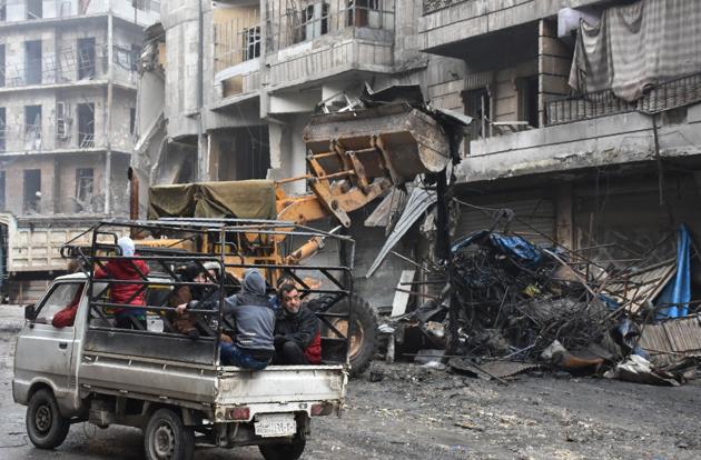 Syrian civilians drive past a tractor removing rubble as the Syrian government starts to clean up areas formerly held by opposition forces in the northern city of Aleppo.(AFP) Syrian civilians drive past a tractor removing rubble as the Syrian government starts to clean up areas formerly held by opposition forces in the northern city of Aleppo.(AFP)