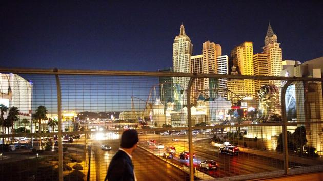FILE - In this Oct. 18, 2016 file photo, the Las Vegas Strip is seen in the background as a pedestrian passes in Las Vegas. More than 300,000 visitors are expected to descend on Las Vegas for an extravagant New Year's Eve celebration. Nightclubs are pulling out all the stops with performances from DJ Calvin Harris, rappers T-Pain and Kendrick Lamar and artists Drake and Bruno Mars. (AP Photo/David Goldman, File) (AP) FILE - In this Oct. 18, 2016 file photo, the Las Vegas Strip is seen in the background as a pedestrian passes in Las Vegas. More than 300,000 visitors are expected to descend on Las Vegas for an extravagant New Year's Eve celebration. Nightclubs are pulling out all the stops with performances from DJ Calvin Harris, rappers T-Pain and Kendrick Lamar and artists Drake and Bruno Mars. (AP Photo/David Goldman, File) (AP)