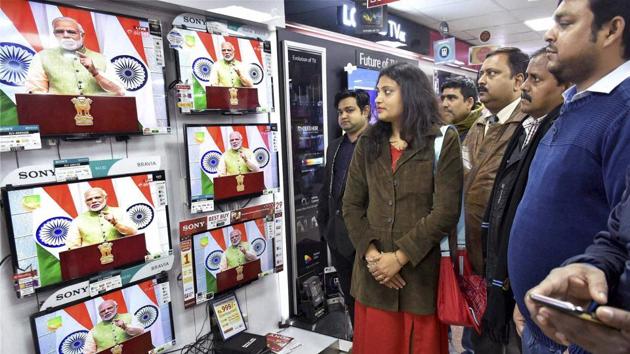 People watching live telecast of Prime Minister Narendra Modi's speech at an electronic shop in Patna on Saturday.(PTI)