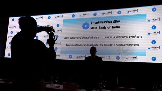 A man takes photo of his colleague with a mobile phone in front of a screen displaying the State Bank of India (SBI) logo before the start of a news conference in Kolkata.(Reuters file) A man takes photo of his colleague with a mobile phone in front of a screen displaying the State Bank of India (SBI) logo before the start of a news conference in Kolkata.(Reuters file)