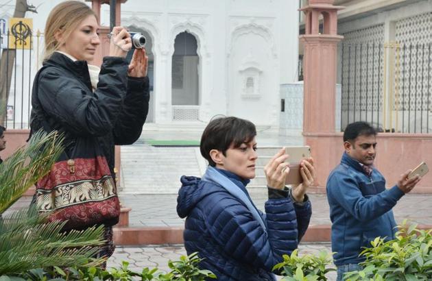 Tourists taking pictures of a nagar kirtan during the 350th birth anniversary celebrations of Guru Gobind Singh, in Amritsar on Tuesday. (Sameer Sehgal/HT)