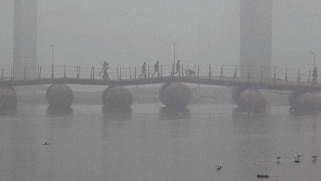 People cross the Pontoon bridge on the river Ganga amid dense fog on a cold morning in Allahabad. (PTI)