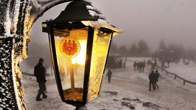 A lamp of a restaurant shines as trippers walk by in thick fog on top of the 880 m high Feldberg mountain near Frankfurt, Germany. (Michael Probst/AP)