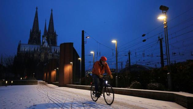 A man cycles through the snow in western Germany, as the Cologne Cathedral looms behind him. (AFP)