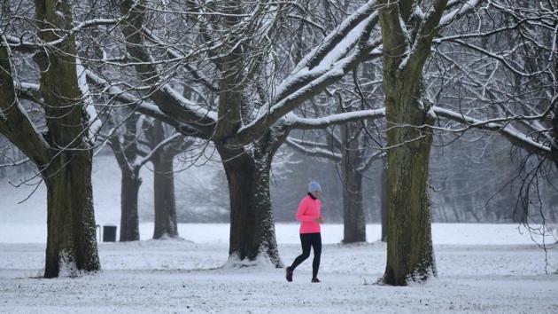 A runner jogs on a snow-covered path in the city park in Cologne, western Germany. (AP)