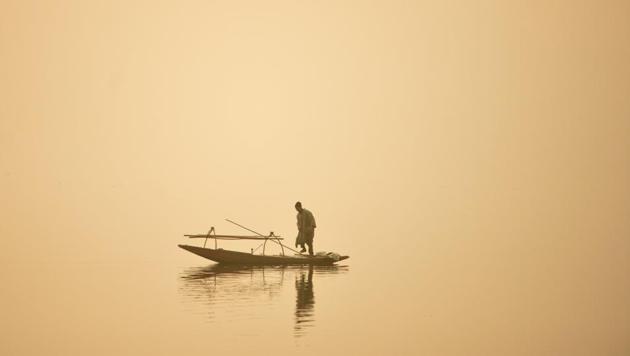 A fisherman sails his boat through dense fog day on the Dal Lake in Srinagar. (ATauseef Mustafa/FP)