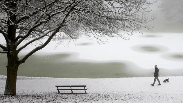 As temperatures continue to drop, many places across the globe are witnessing heavy snowfall. A man walks his dog through a snow-covered park in Brussels, Belgium. (REUTERS)