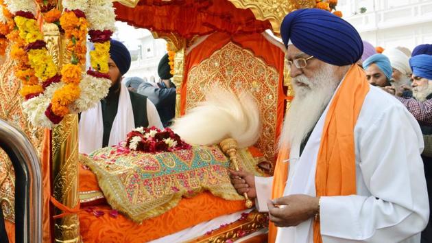 Sikh devotees carry Sri Guru Granth Sahib Ji, the holy book of the Sikh religion, in a special golden palanquin at the Golden Temple during Nagar Kirtan on the eve of 350th birth anniversary of Guru Gobind Singh, Amritsar on Wednesday.  (Sameer Sehgal / HT Photo) 