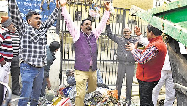 Dozens of municipal workers dumped garbage and shouted slogans outside Deputy CM Manish Sisodia’s camp office in New Delhi on Friday.(Mohd Zakir/Hindustan Times)