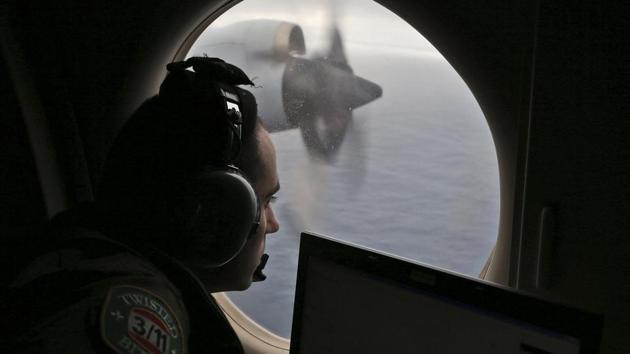 In this March 22, 2014 file photo, flight officer Rayan Gharazeddine scans the water in the southern Indian Ocean off Australia from a Royal Australian Air Force AP-3C Orion during a search for the missing Malaysia Airlines Flight MH370.(AP Photo)