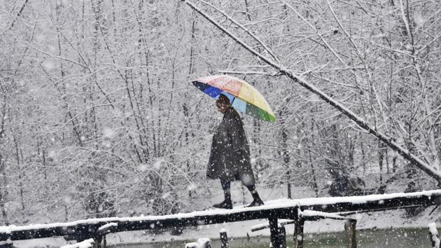A boy with a rainbow colour umbrella walks on a foot bridge during a snowfall on January 6, 2017 in Srinagar, India. (Waseem Andrabi / HT Photo)