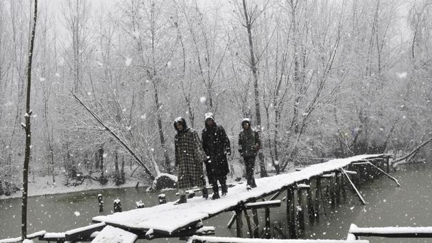 Kashmiri men walk on a foot bridge during a snowfall on January 6, 2017 in Srinagar, India. (Waseem Andrabi / HT Photo)