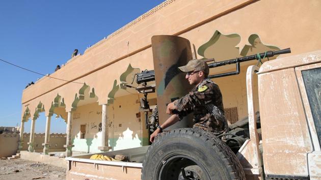 A Syrian Democratic Forces (SDF) fighter sits on the back of a pick-up truck with a weapon installed on it, in Tal Samin village, north of Raqqa city, Syria.(Reuters)