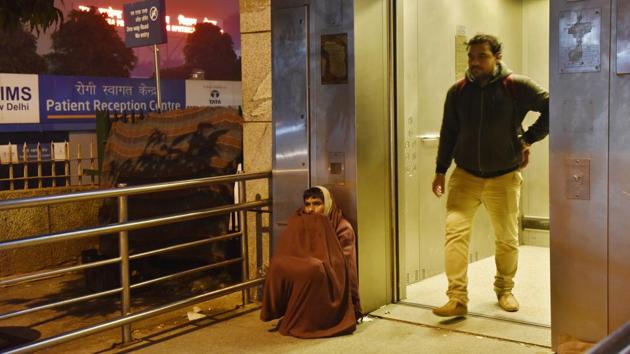 A man sits outside an elevator at AIIMS metro station on a cold winter night. (Saumya Khandelwal/HT PHOTO) 
