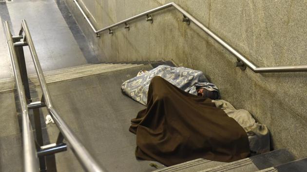 People seek refuge from the cold on the stairs of the AIIMS metro station. (Saumya Khandelwal/HT PHOTO) 