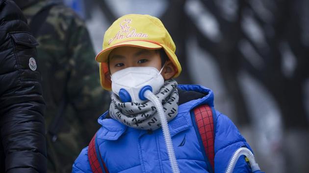 A boy wears a mask as he walks along road in Beijing on Thursday.(AFP Photo)