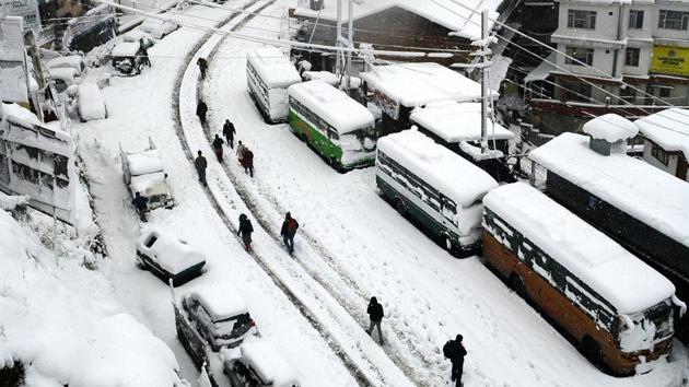 People walk through a snow-covered road  at Sanjauli. Electricity supply was snapped here and in Manali, as power lines were damaged due to falling trees. (Deepak Sansta/HTPhoto) 