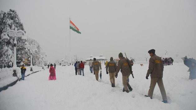 Police personnel walk across the snow-covered historical site 'The Ridge’. (PTI) 