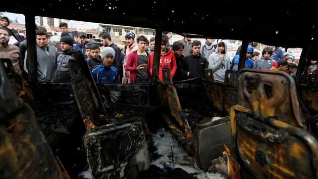 People look at a burned vehicle at the site of a car bomb attack in a busy square at Baghdad's sprawling Sadr City district in Iraq on January 2. (REUTERS)