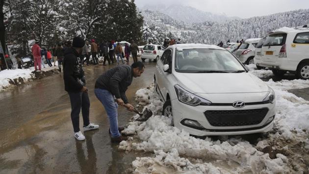 A tourist tries to clear snow from beneath vehicles stranded due to heavy snow fall on the Jammu-Srinagar highway at Patnitop in Udhampur district of Jammu and Kashmir. Due to heavy snowfall, the Kashmir region was cut off from the rest of the country for three days till Sunday. (AP) 