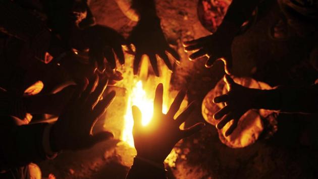 Labourers warm up in front of a  bonfire on a cold winter morning in Lucknow. (Deepak Gupta / HT photo) 