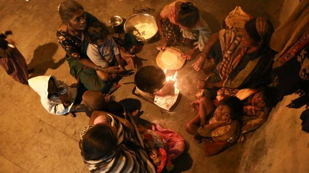 FOR THE SAKE OF LOVE: A group of women and children at Motia Khan huddles around a fire to keep warm while a woman cooks rotis for dinner.  (AMAL KS/HT PHOTO) 