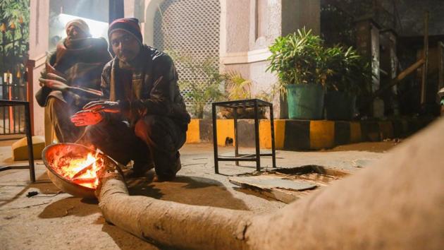 LIFE ON FIRE: While they keep watch outside a society at Mall Road, security guards warm themselves up with small bonfire. (AMAL KS/HT PHOTO) 