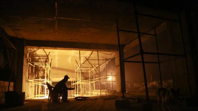 ON DUTY: A solitary security guard tries to keep himself warm at night at Lajpat Rai Market, Old Delhi. (AMAL KS/HT PHOTO) 