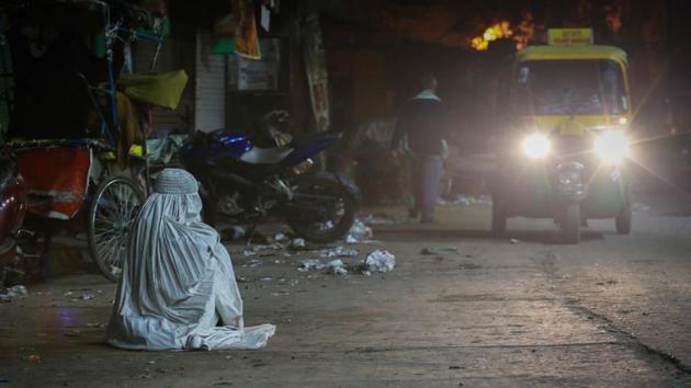 WAITING IN WHITE: A person wearing an Afghani burkha sits alone on the road at 4am near Turkman Gate. (AMAL KS/HT PHOTO) 