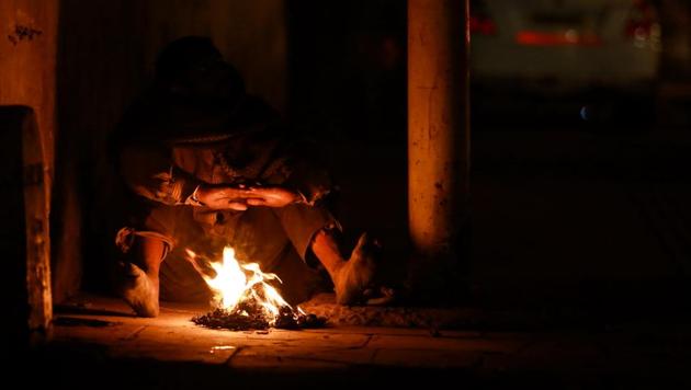 WASTE NOT: A man sits barefoot and burns waste plastic bottles from garbage bins to keep himself warm at Turkman Gate, Old Delhi. (AMAL KS/HT PHOTO) 
