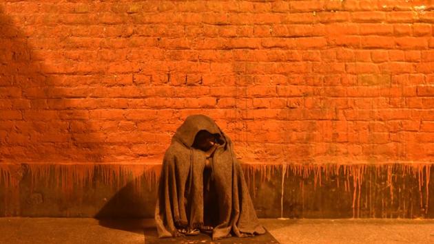 A homeless man sits on the pavement on a cold winter night near Yamuna Bazar in New Delhi. (Vipin Kumar/HT PHOTO)
