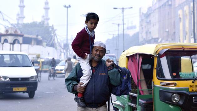 A man carries his son to school on his shoulders on a cold winter morning in Old Delhi. (Arun Sharma/HT PHOTO)