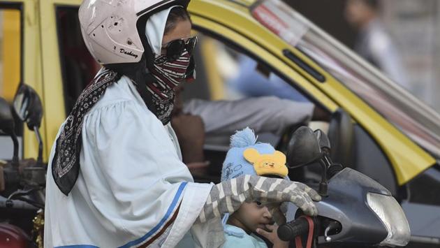 A little girl sports a woolen cap while traveling on scooter with parent as the city temperature continues to dip in Mumbai. (Arijit Sen/HT PHOTO)