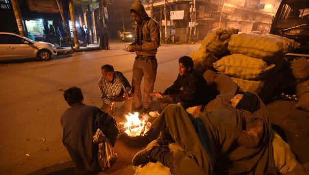 Homeless men sitting near the fire to stay warm on a cold winter morning in New Delhi. (Arun Sharma/HT PHOTO)