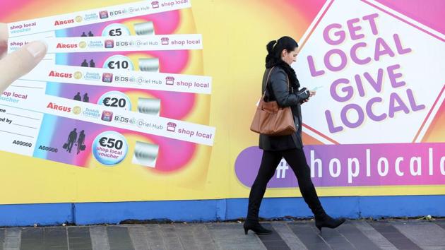 A woman walks past a poster advertising vouchers, a form of alternative currency aimed at boosting local shopping in the border town of Dundalk, Northern Ireland. (AFP Photo) A woman walks past a poster advertising vouchers, a form of alternative currency aimed at boosting local shopping in the border town of Dundalk, Northern Ireland. (AFP Photo)