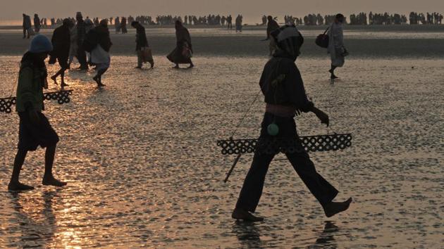 Local village boys walk with magnets to attract coins offered by pilgrims on Makar Sankranti festival in Gangasagar on Saturday. Thousands of devotees gather to take holy dips which they believe absolves them of sin. (AP) Local village boys walk with magnets to attract coins offered by pilgrims on Makar Sankranti festival in Gangasagar on Saturday. Thousands of devotees gather to take holy dips which they believe absolves them of sin. (AP)