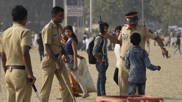 A police officer snatches the kite threads from a child at Girgaum beach. (Arijit Sen/HT PHOTO)