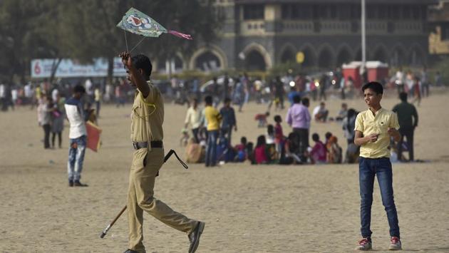 A child looks on as a police constable takes away his kite at Girgaum beach. (Arijit Sen/HT PHOTO)