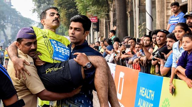 Pramod Nair, a  participant of half marathon was carried by a policemen and a volunteer during half marathon. (kunal patil/ht photo) 