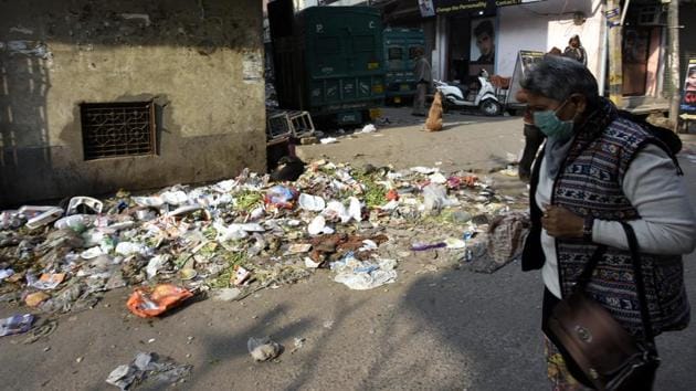 A woman covers her face as she walks past a garbage dump on Krishna Nagar road. (Sonu Mehta/HT) A woman covers her face as she walks past a garbage dump on Krishna Nagar road. (Sonu Mehta/HT)