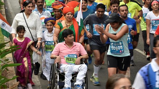 An athlete cheers for a participant on wheel-chair during Mumbai Marathon. (Arijit Sen/HT PHOTO) 