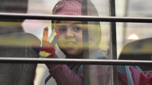 A girl waves to her parents as she boards her school bus early morning in New Delhi. (Raj K Raj/HT PHOTO)