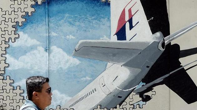 This file picture taken on March 8, 2016 shows a man walking in front of a mural of missing Malaysia Airlines MH370 plane in a back-alley in Shah Alam, Malaysia.(AFP File Photo)