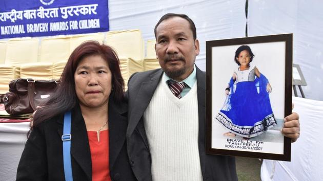 Tarh Peeju’s parents hold a picture of their daughter who won an award (Posthumously) for saving two children from drowning in a river, losing her life because of strong undercurrents. (Mohd Zakir/HT Photo)