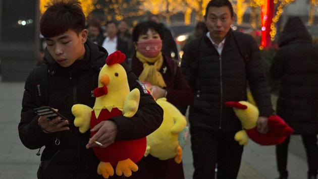 People carry rooster dolls in Beijing on Monday, to celebrate the Lunar New Year on Jan 28 this year. 2017 is the Year of the Rooster in the Chinese calendar. (Ng Han Guan / AP)